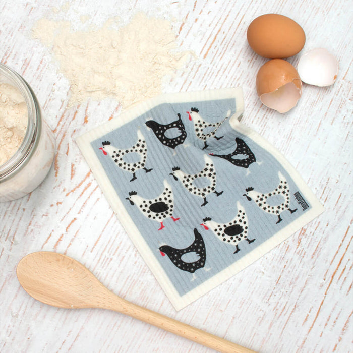 Compostable sponge cloth with a hen design on a bench.