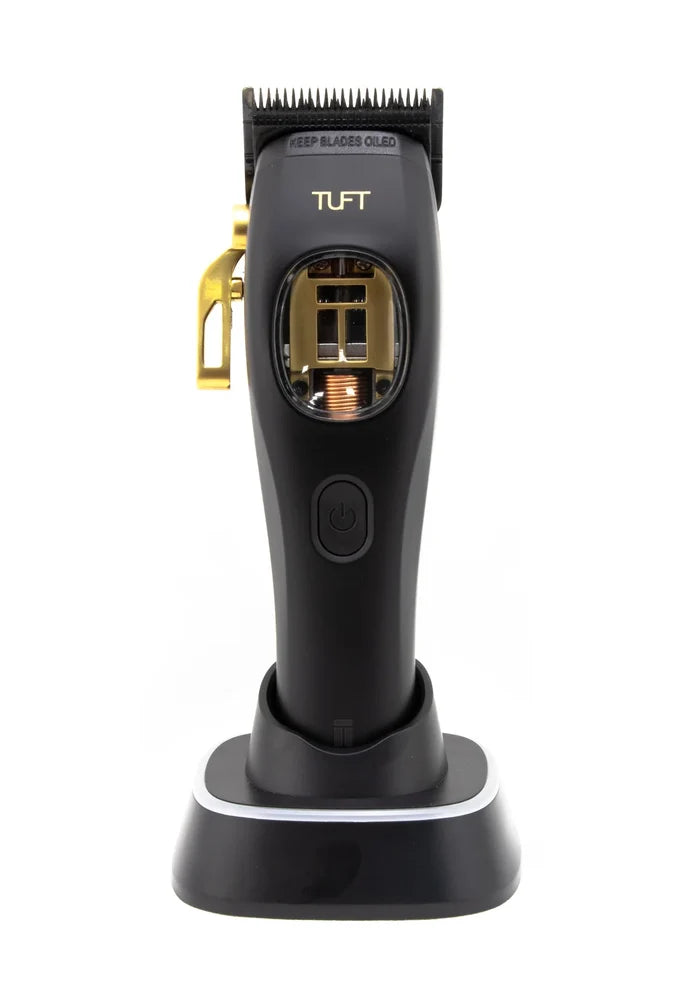 A black and gold TUFT clipper standing on its charging base against a white background.