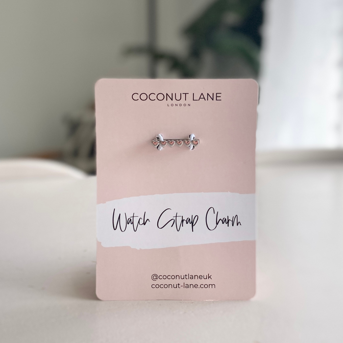 Silver heart watch strap charm from Coconut Lane, shown on a pink card.