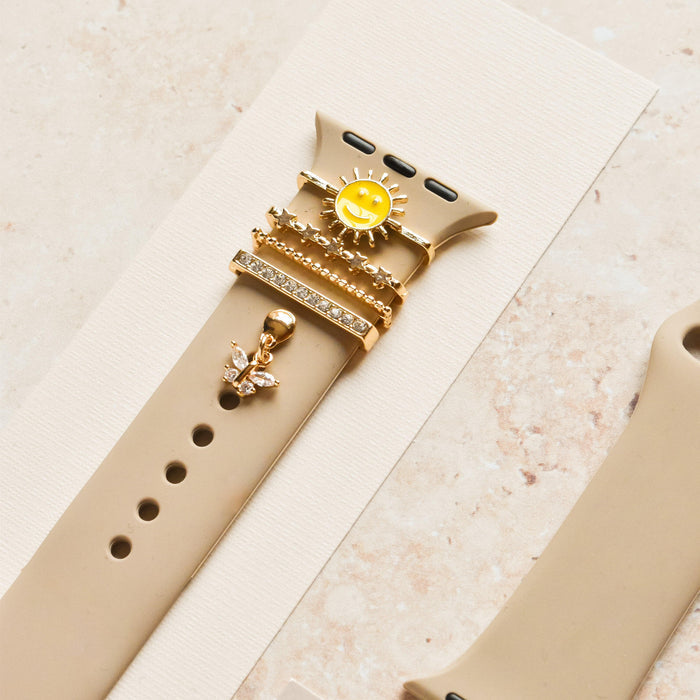 Beige silicone watch strap with a gold smiley sun charm, Coconut Lane.