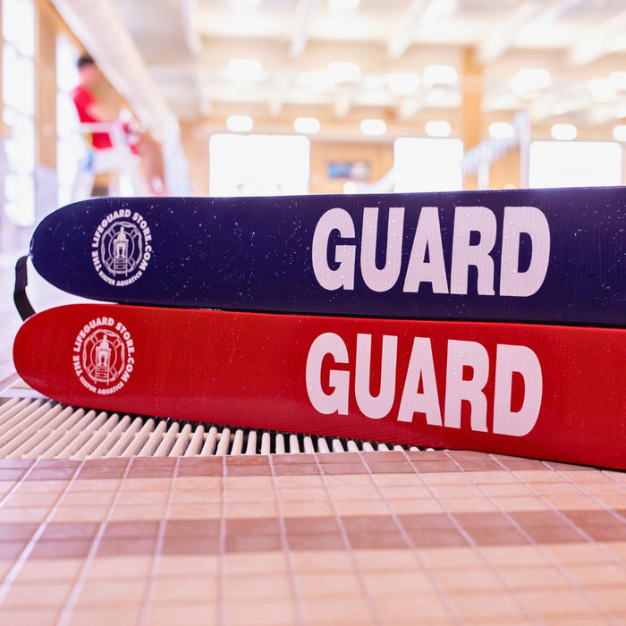 The Lifeguard Store blue and red 40" rescue tubes with "GUARD" printed in white, poolside.