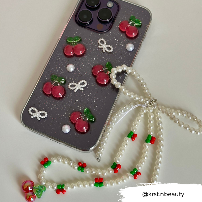 Cherries & Bows phone case with a matching beaded pearl strap, both featuring red cherry patterns.