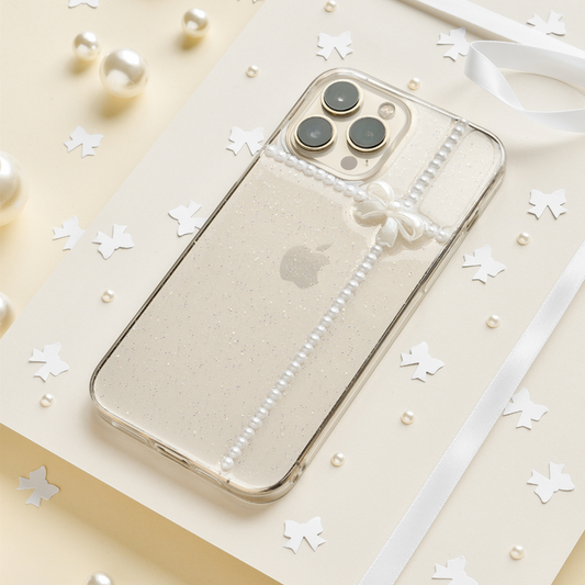 Clear iPhone 15 case with pearl and bow accents on a cream background by Coconut Lane.
