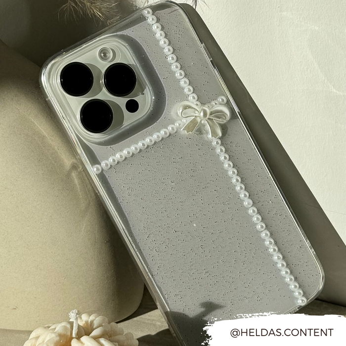 Clear iPhone 15 case with pearl-like beads and a small decorative bow by Coconut Lane.