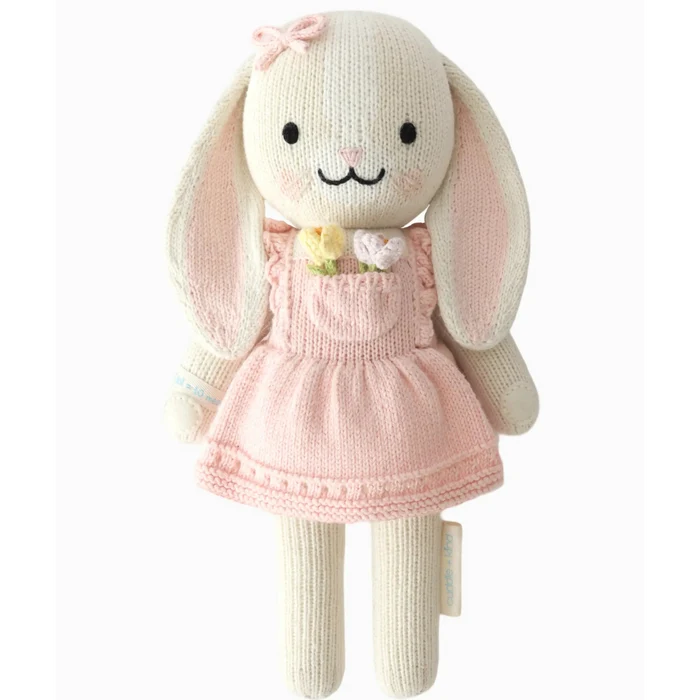 Knitted bunny toy with a pink dress on a white background