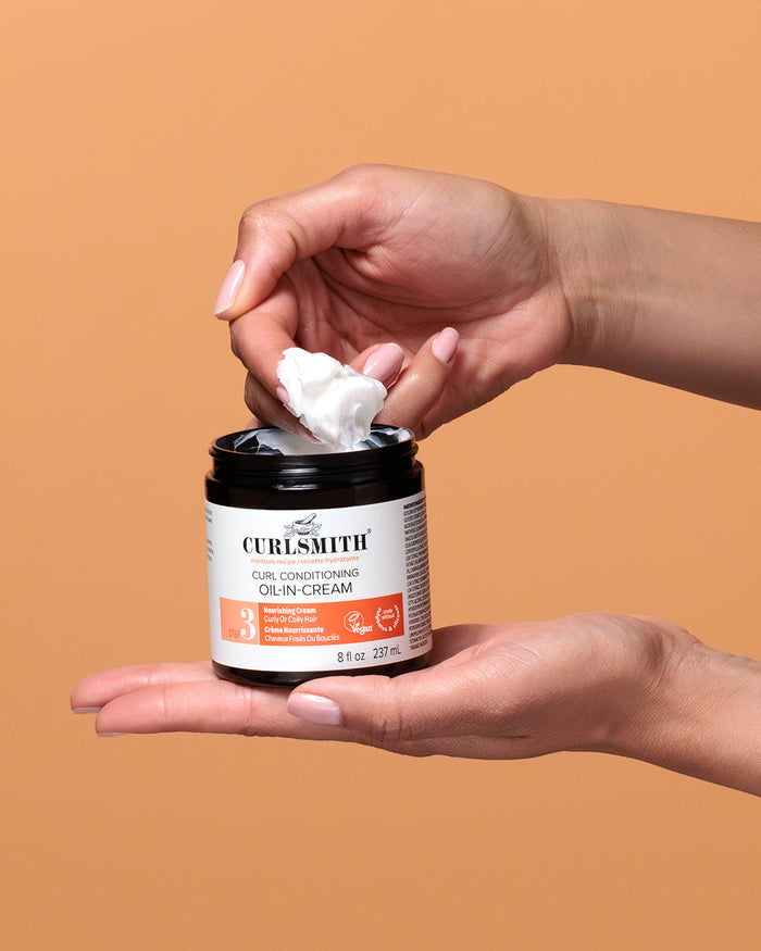 Person holding a jar of Curlsmith product with a brown background
