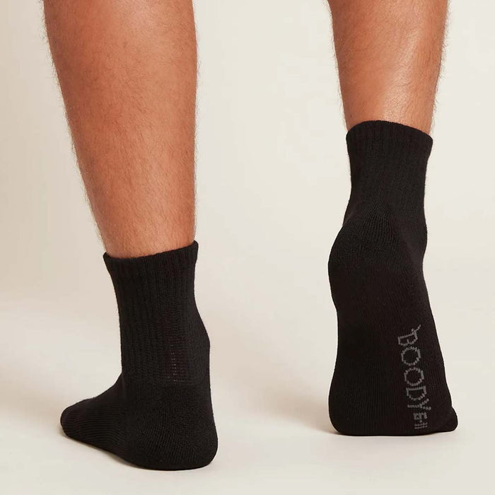 A pair of black quarter crew socks modelled on a male's feet.