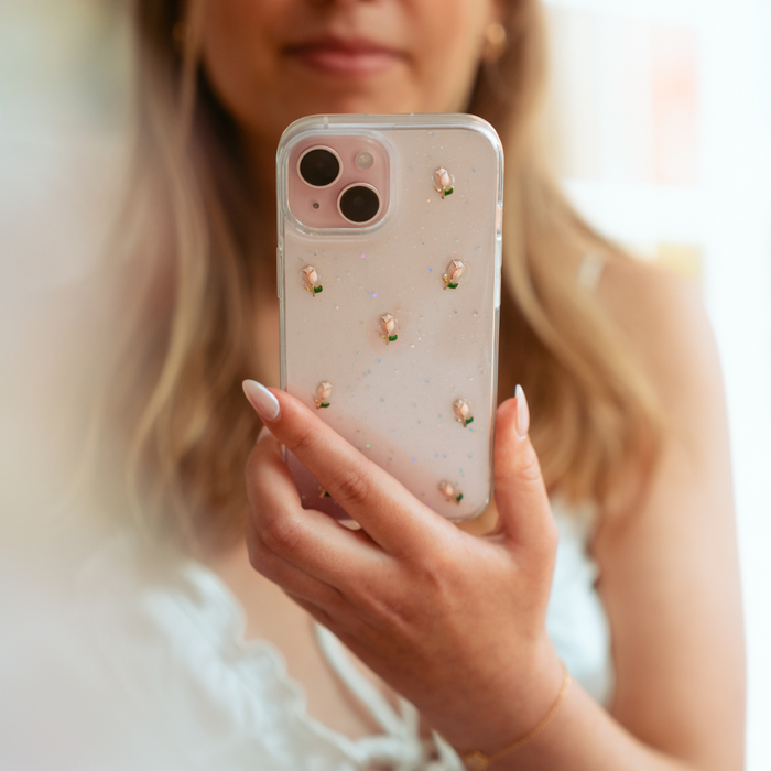 Clear phone case with colorful tulip pattern held in womans hand, designed for iPhone 15.