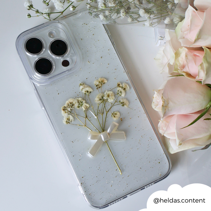 Clear iPhone 15 case with white dried flowers and a small bow design, by Coconut Lane.