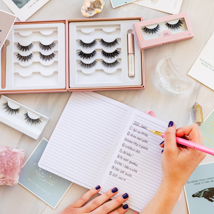 A woman writing in a notebook and Lash Story Visionary filled with lashes.