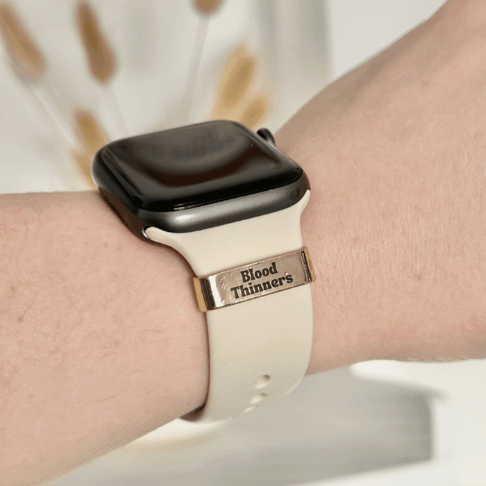 Cream smartwatch band with a Coconut Lane charm that reads Blood Thinners.