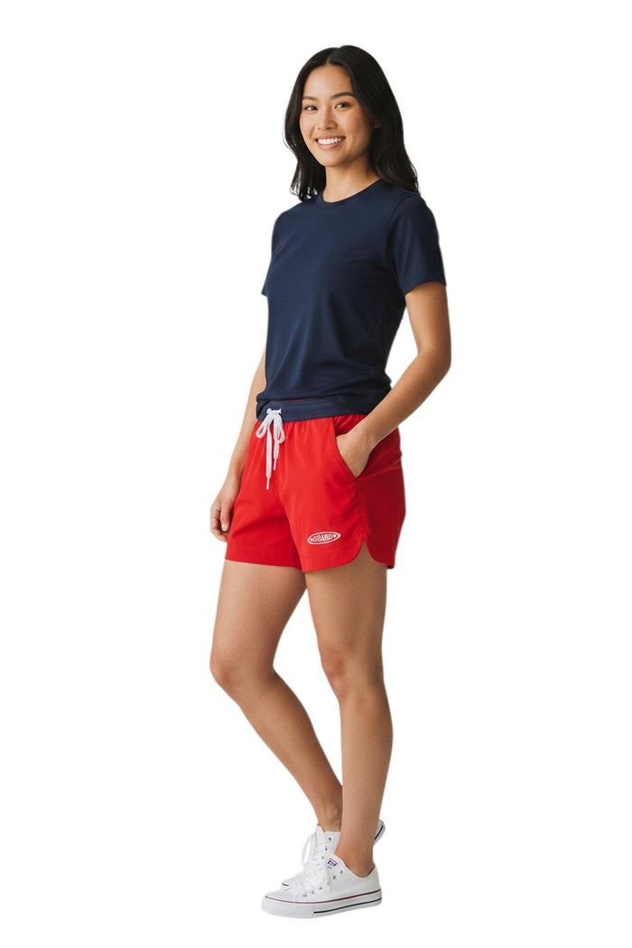 The Lifeguard Store RISE Guard red polyester roll shorts with navy waistband and white drawstring, 4-inch inseam.