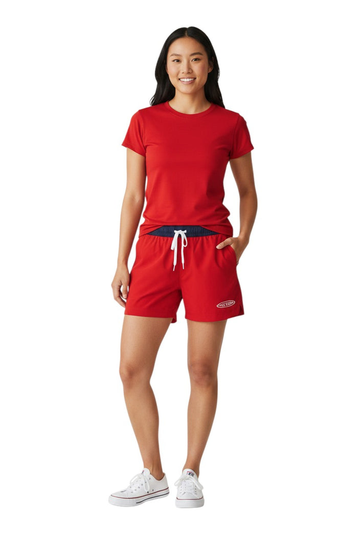 The Lifeguard Store RISE Guard red polyester roll shorts with navy waistband and white drawstring, 4-inch inseam.