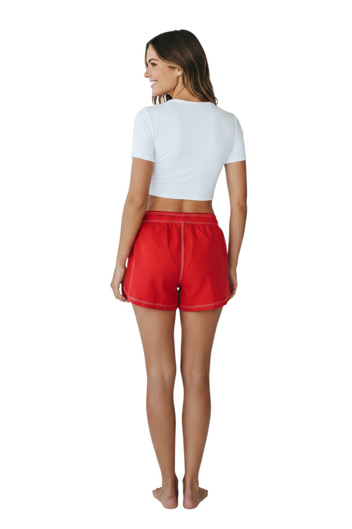 The Lifeguard Store red polyester flex shorts with elastic waistband, drawstring, and side pocket. Approximately 5" inseam.