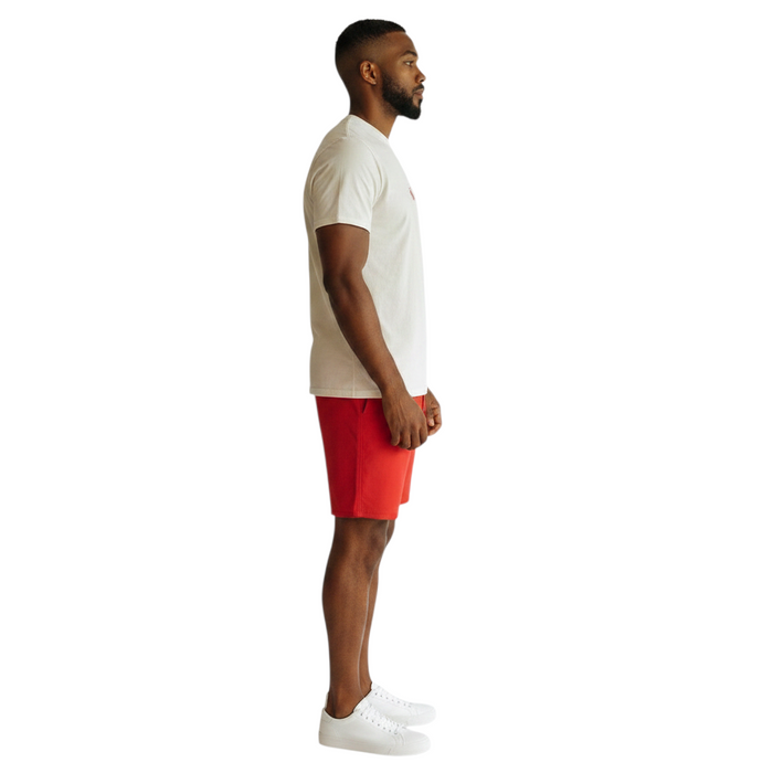 The Lifeguard Store staff tee in white cotton worn by a man in profile with red shorts and white sneakers