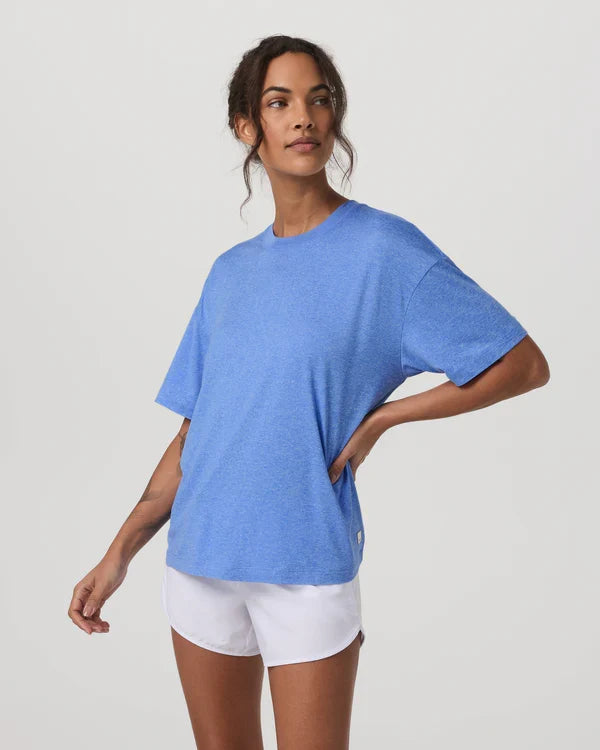 Woman wearing a Vuori - Energy Tee Long and white shorts on a light gray background