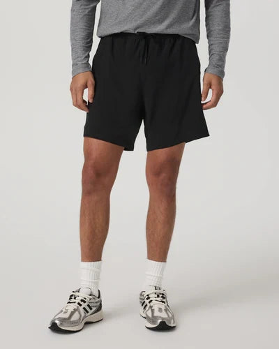 Person wearing black Vuori Kore shorts and gray sneakers on a white background