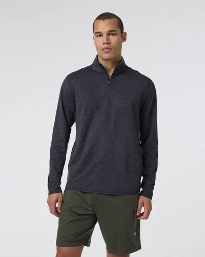 Man wearing a Vuori - Ponto 1/2 Zip Mock Neck and green shorts on a white background