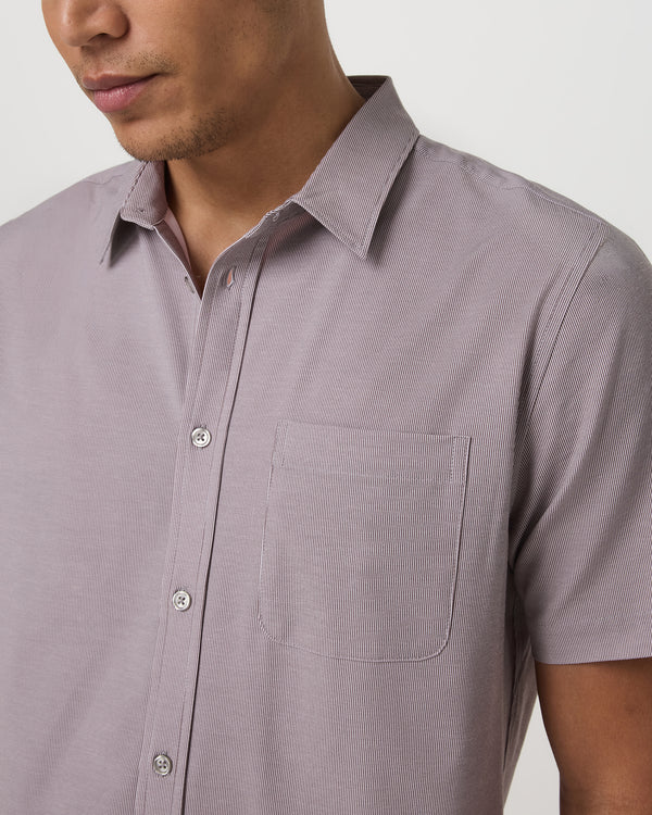 Close-up of a man wearing a Vuori gray short-sleeve shirt with a pocket on a light gray background