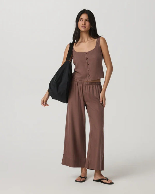 Woman wearing Vuori - Trestles Twill Crop Wideleg Pant holding a black bag on a white background