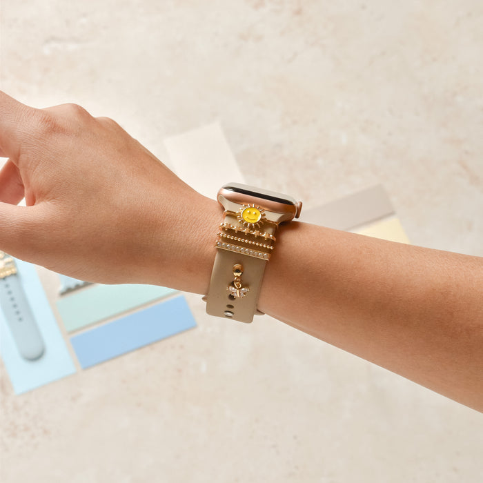 Gold Smiley Sun watch strap charm by Coconut Lane on a smartwatch, displayed above colorful swatches.